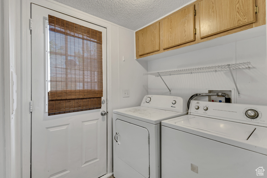 Laundry room featuring a textured ceiling, cabinet space, and washer and dryer