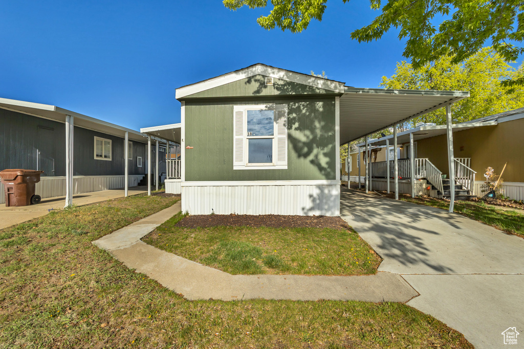 Manufactured / mobile home with an attached carport, driveway, and a front yard