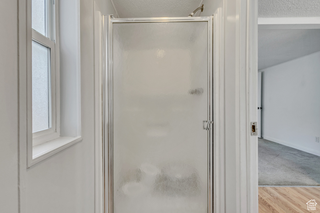 Full bathroom featuring baseboards, a stall shower, a textured ceiling, and wood finished floors