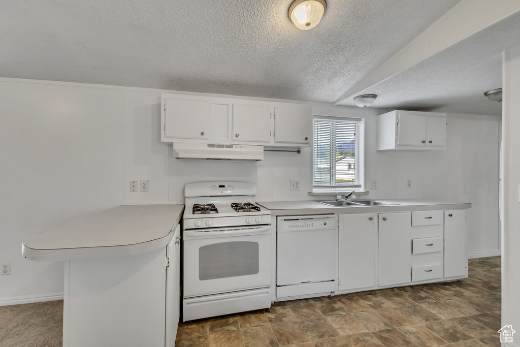 Kitchen with a peninsula, white appliances, light countertops, under cabinet range hood, and a sink