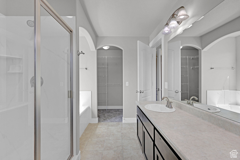 Full bath featuring vanity, tile patterned floors, a walk in closet, and a stall shower