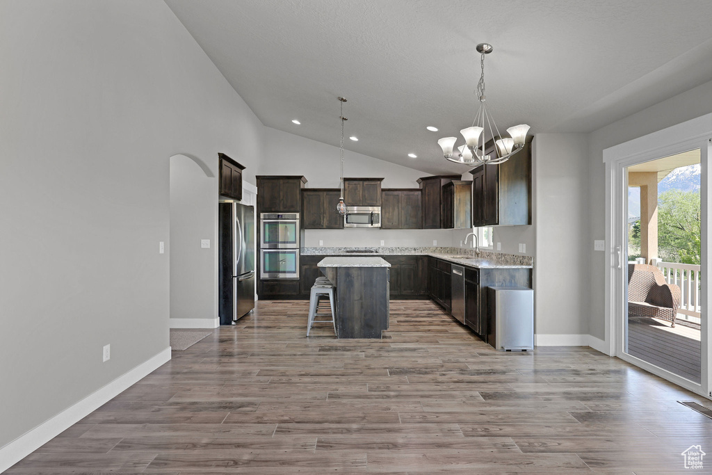 Kitchen with dark brown cabinets, a breakfast bar area, recessed lighting, a notable chandelier, and stainless steel appliances