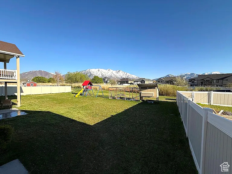 View of yard with a fenced backyard, a playground, and a mountain view