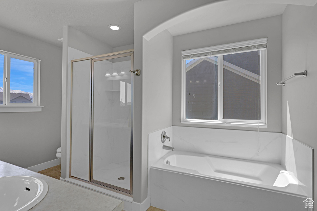 Bathroom with a sink, toilet, baseboards, a shower stall, and a garden tub