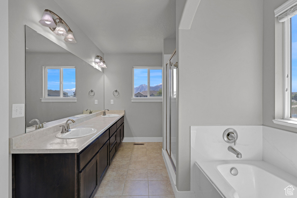 Bathroom featuring tile patterned flooring, a sink, and a wealth of natural light