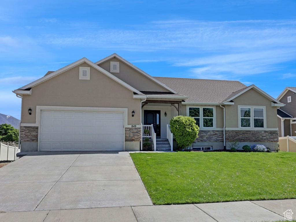 View of front of home with a garage, fence, concrete driveway, stone siding, and stucco siding