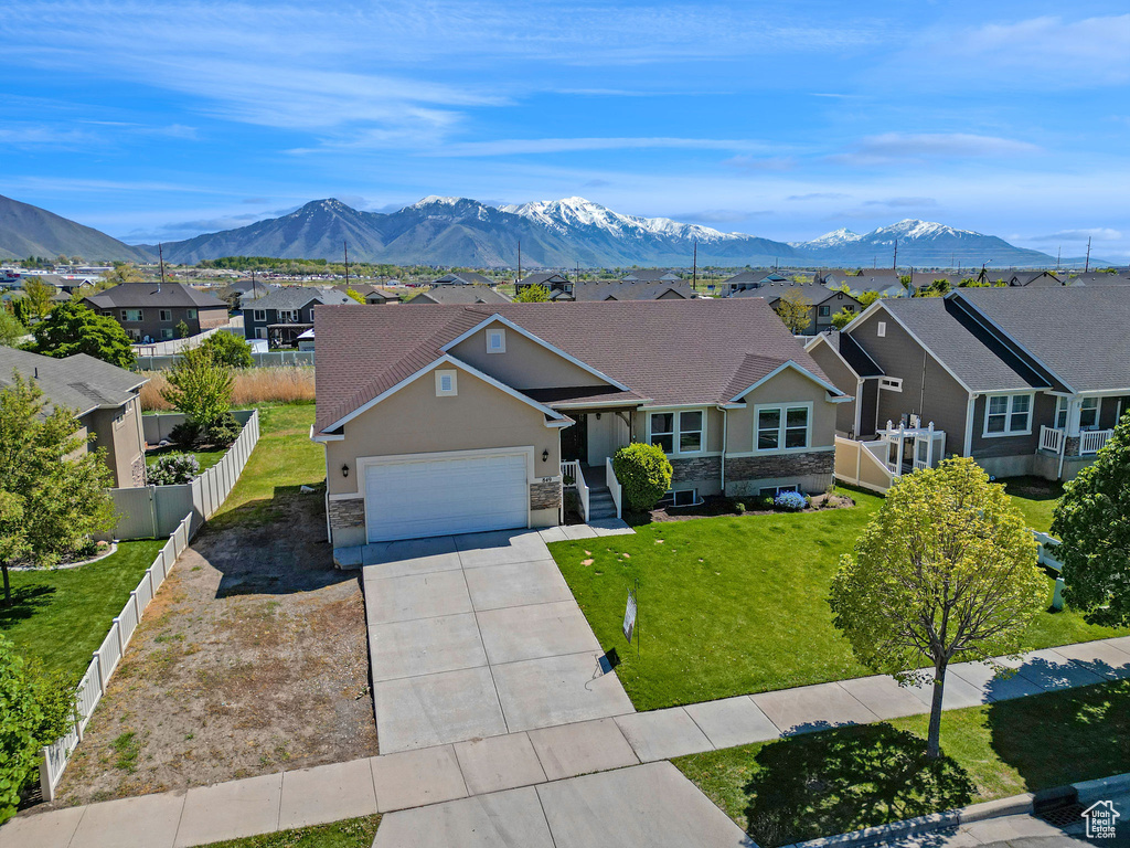 Ranch-style house with concrete driveway, a residential view, stone siding, and a garage