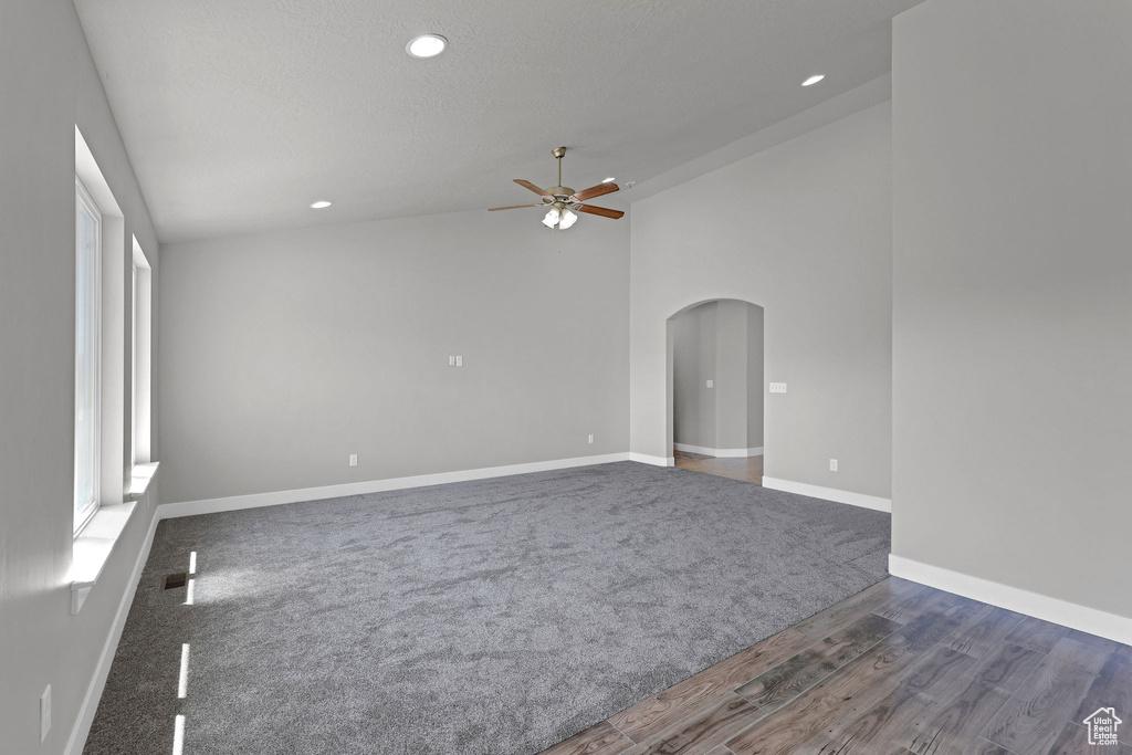 Empty room featuring ceiling fan, arched walkways, recessed lighting, baseboards, and lofted ceiling