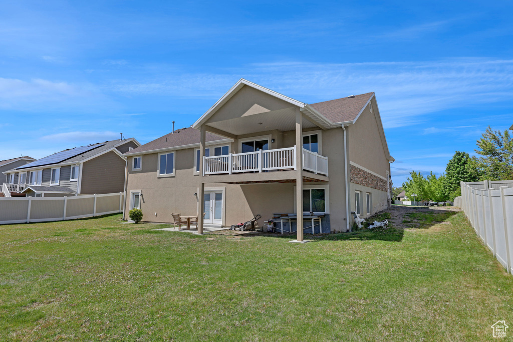 Rear view of property with a lawn, a fenced backyard, stucco siding, and french doors