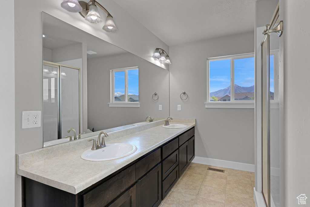 Full bath with double vanity, baseboards, visible vents, and a sink