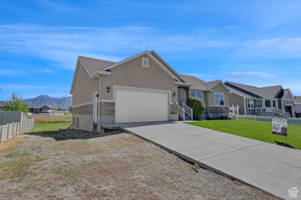Single story home with a garage, fence, stone siding, stucco siding, and driveway
