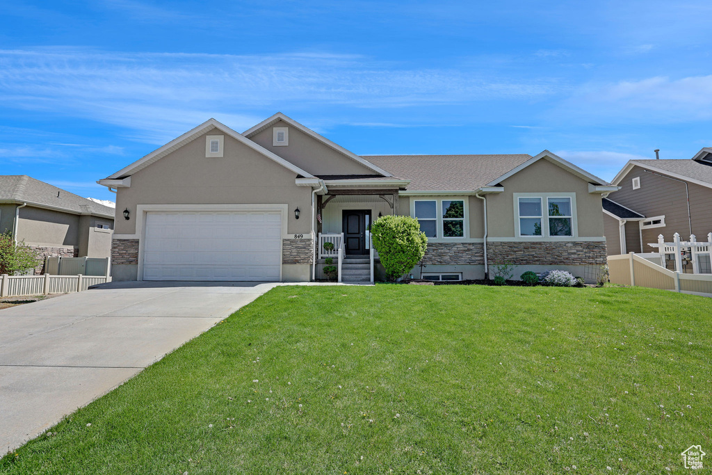 Single story home with driveway, a garage, fence, stone siding, and stucco siding