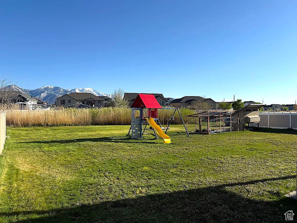 View of play area with a lawn and fence