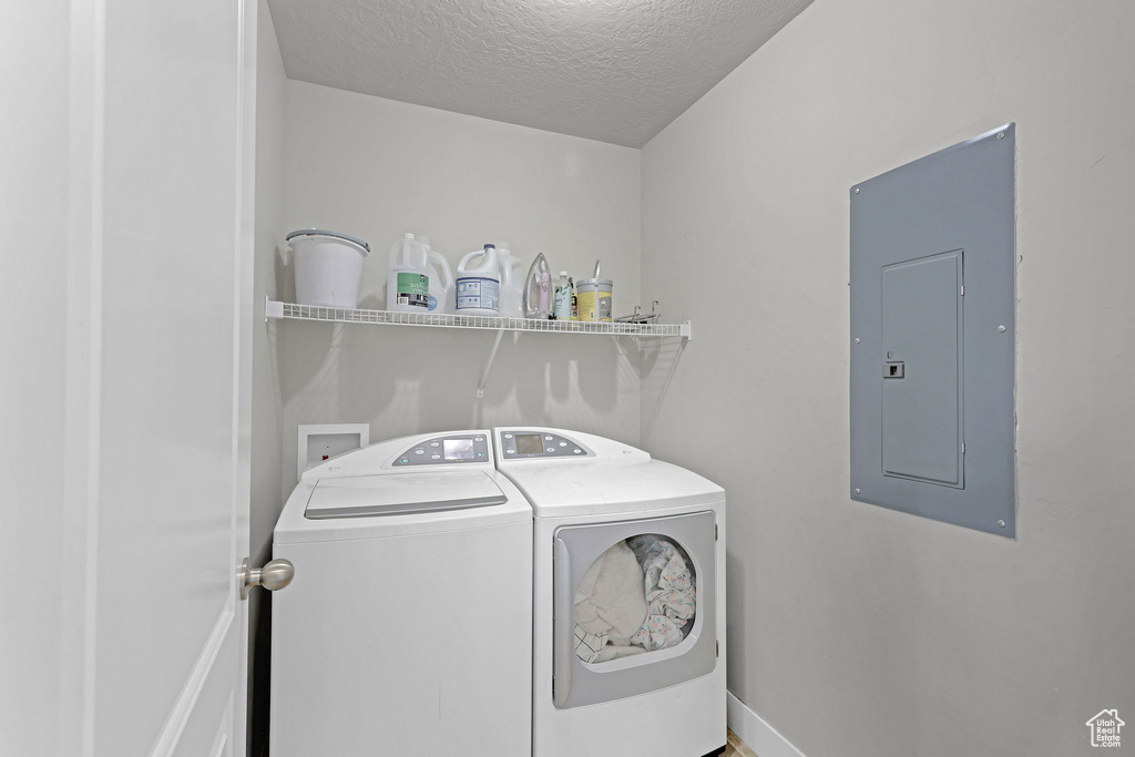 Laundry area with separate washer and dryer, laundry area, a textured ceiling, and electric panel