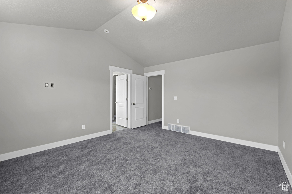 Unfurnished bedroom featuring carpet floors, baseboards, lofted ceiling, and visible vents
