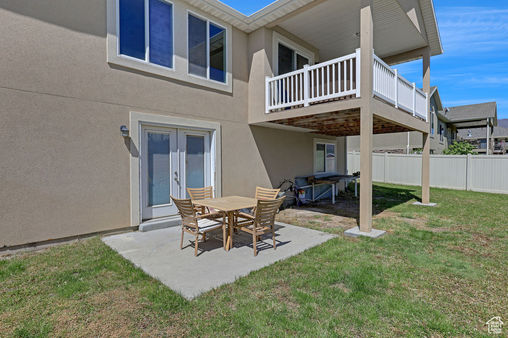Rear view of house with fence, a patio, stucco siding, french doors, and a lawn