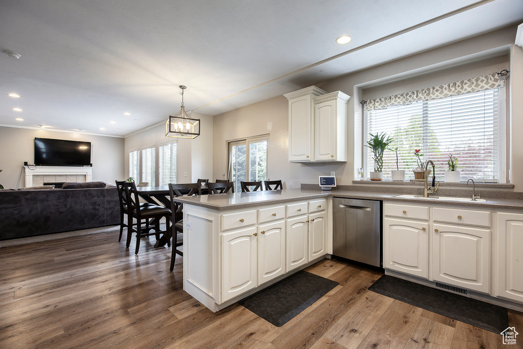Kitchen with white cabinets, dishwasher, a peninsula, open floor plan, and wood finished floors