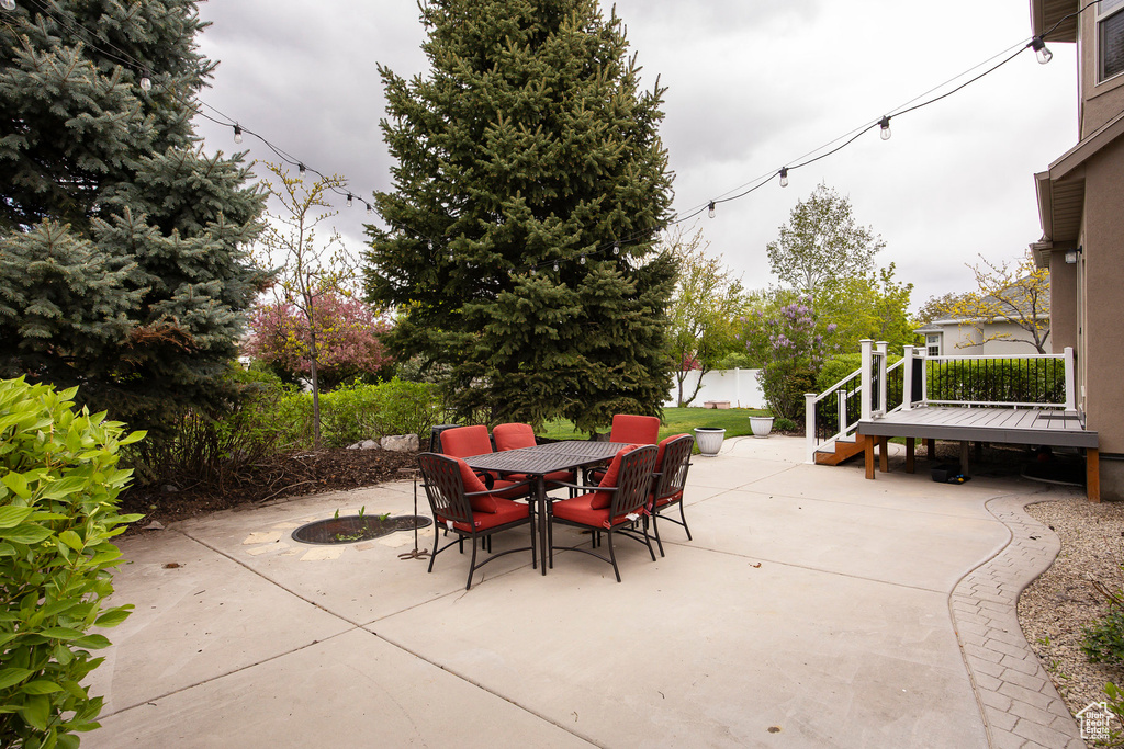 View of patio featuring fence, a wooden deck, and outdoor dining space