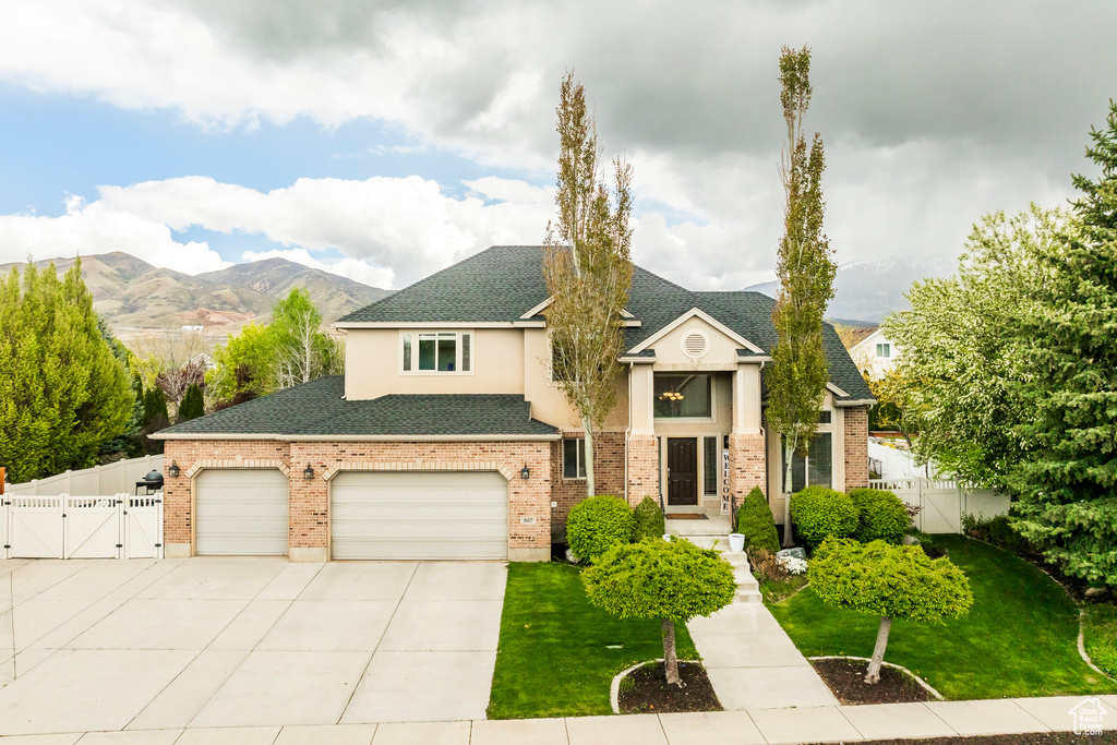 View of front facade featuring fence, a front yard, a gate, a shingled roof, and concrete driveway