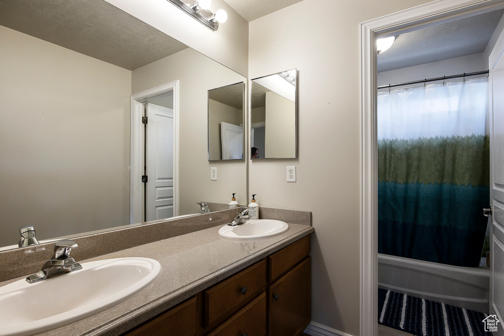 Full bath featuring double vanity, a sink, and shower / tub combo