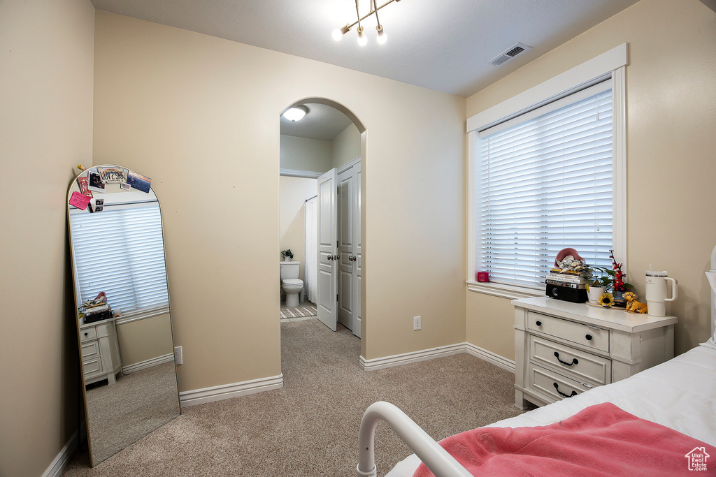 Bedroom with arched walkways, baseboards, light carpet, and visible vents