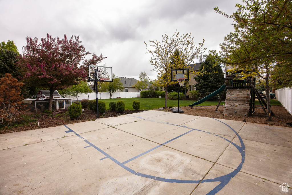 View of sport court with a playground, basketball court, and fence