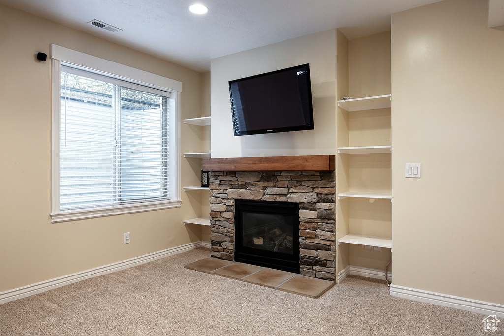 Unfurnished living room featuring baseboards, carpet flooring, visible vents, and a fireplace