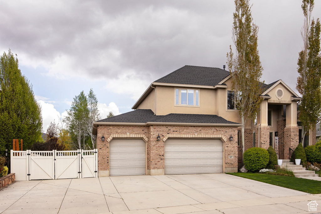Traditional-style home featuring fence, stucco siding, a gate, concrete driveway, and an attached garage