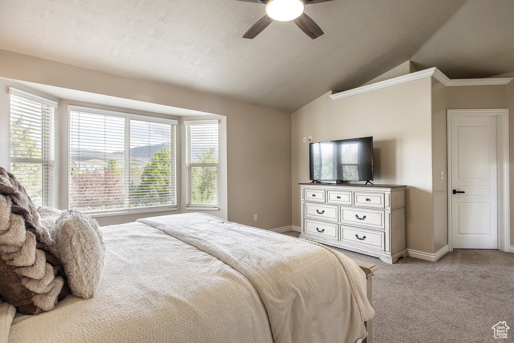 Bedroom featuring a ceiling fan, baseboards, light colored carpet, and lofted ceiling