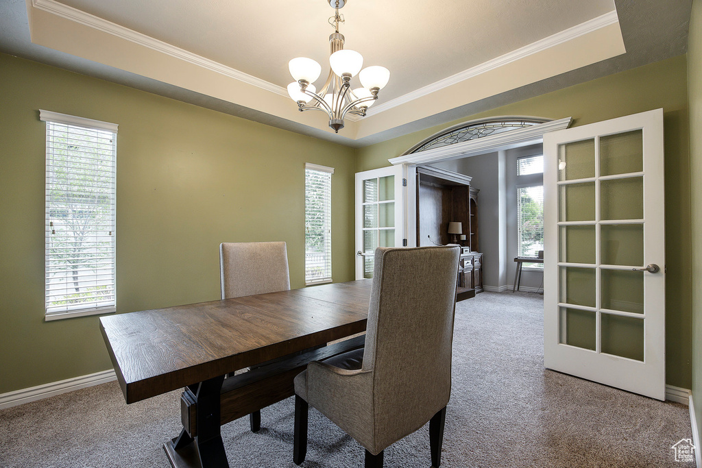 Dining space featuring carpet floors, a tray ceiling, and a notable chandelier