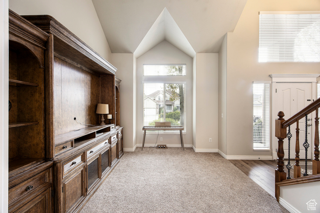 Interior space with stairs, baseboards, light carpet, and lofted ceiling