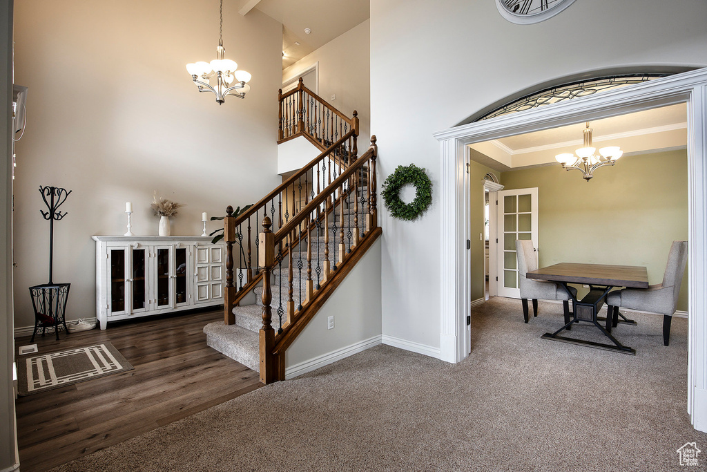 Stairs featuring baseboards, carpet, a towering ceiling, and a notable chandelier