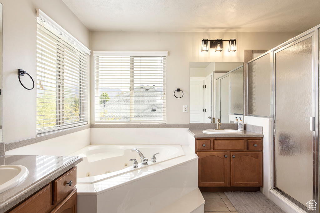 Bathroom with a sink, a jetted tub, a stall shower, and two vanities