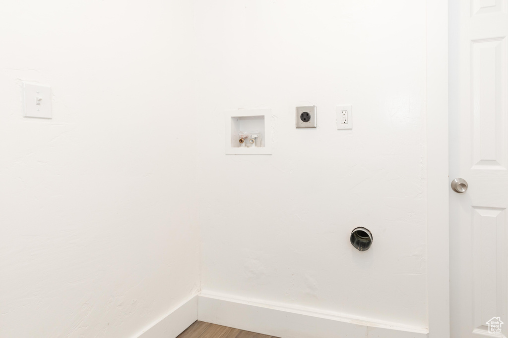 Clothes washing area featuring hookup for an electric dryer, wood finished floors, washer hookup, and laundry area