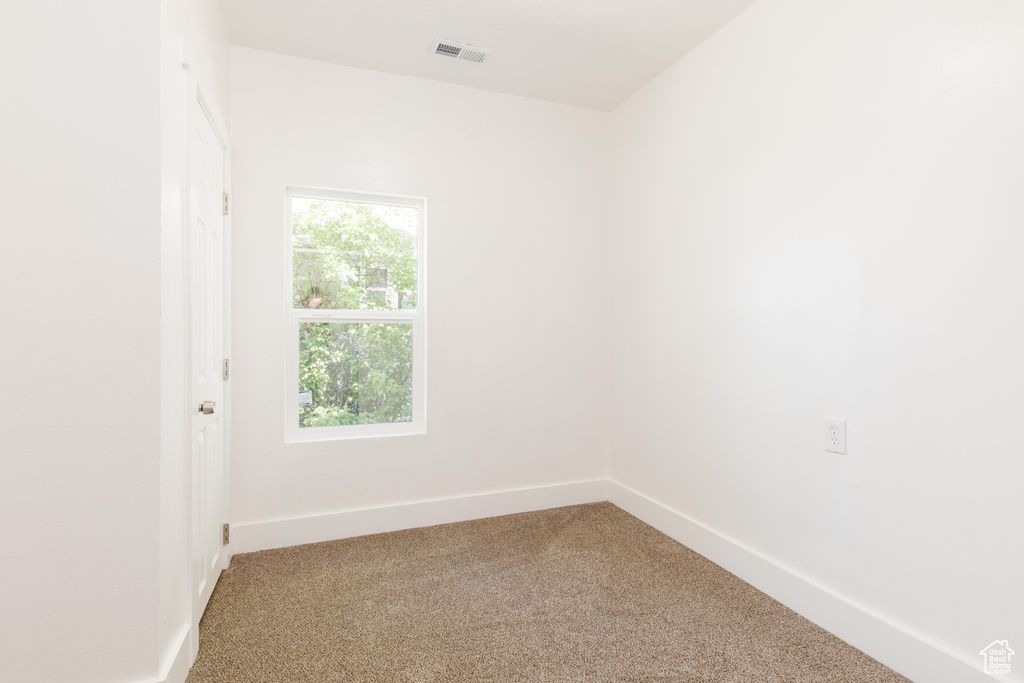 Empty room featuring baseboards, visible vents, and light carpet
