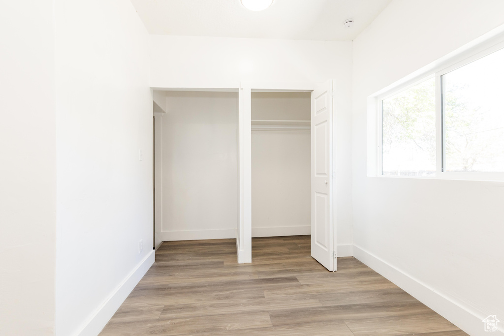 Unfurnished bedroom with baseboards, a closet, and light wood-style flooring