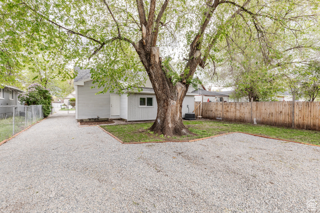 Back of property featuring central air condition unit, roof with shingles, and fence