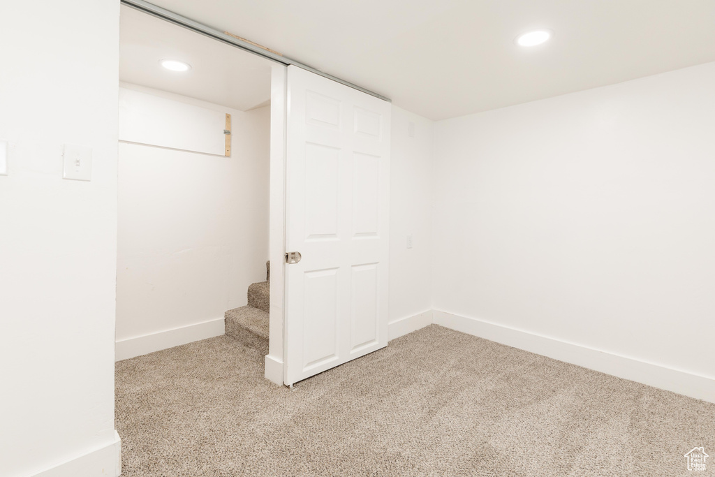 Finished below grade area with baseboards, light carpet, recessed lighting, and stairs
