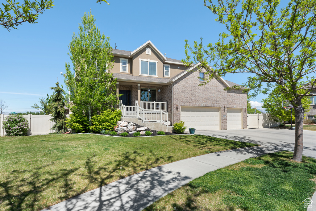 View of front of home featuring fence, an attached garage, a porch, and brick siding