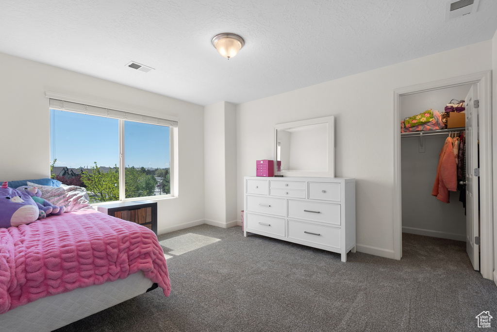 Bedroom featuring visible vents, carpet flooring, baseboards, and a walk in closet