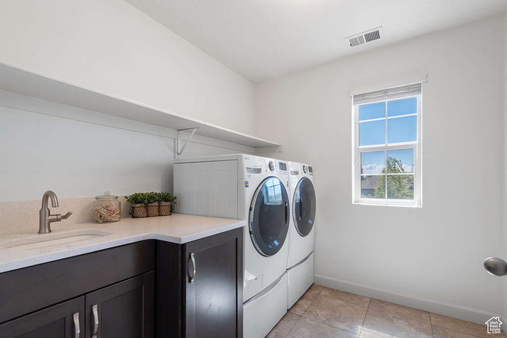 Laundry area with visible vents, washing machine and dryer, baseboards, a sink, and light tile patterned floors