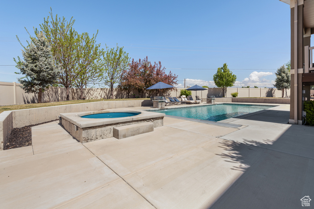 View of swimming pool with a fenced backyard, a fenced in pool, an in ground hot tub, and a patio area