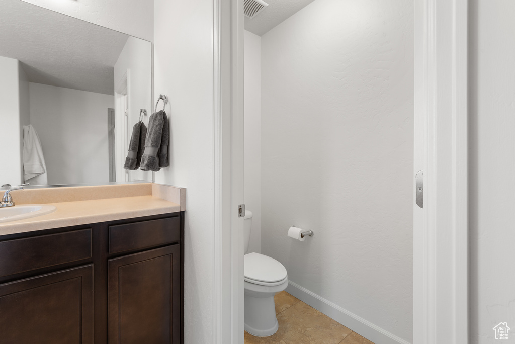 Bathroom featuring vanity, toilet, tile patterned floors, baseboards, and visible vents