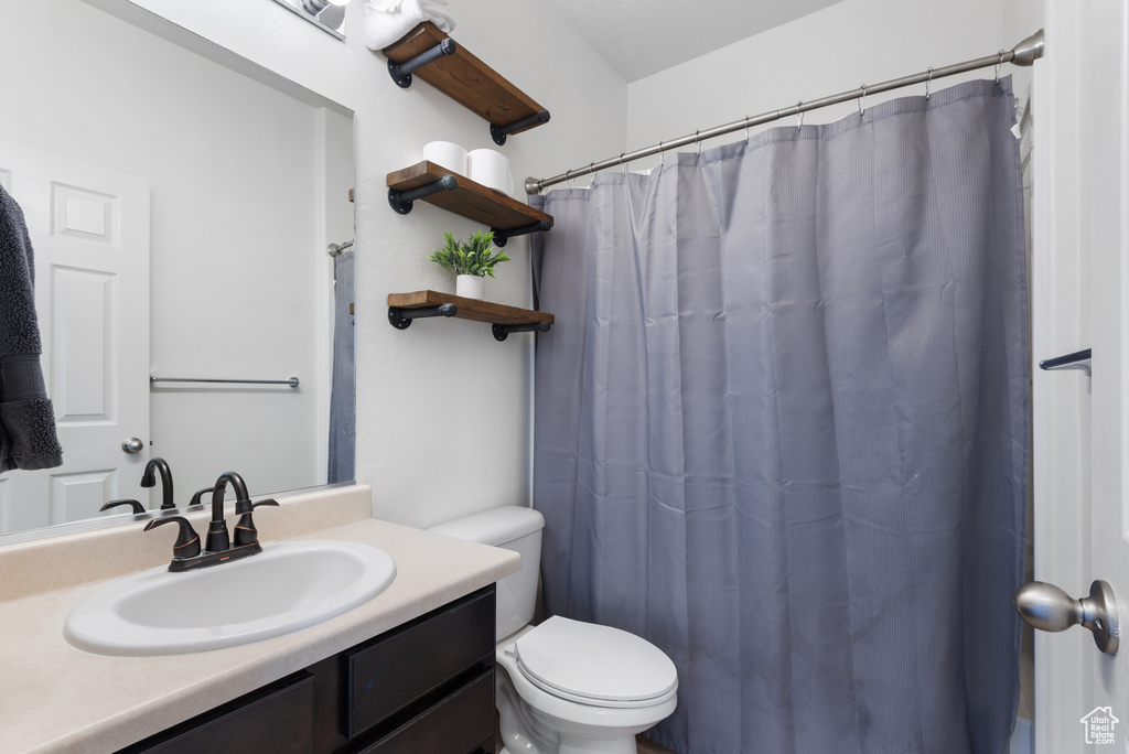 Bathroom with vanity, curtained shower, and toilet