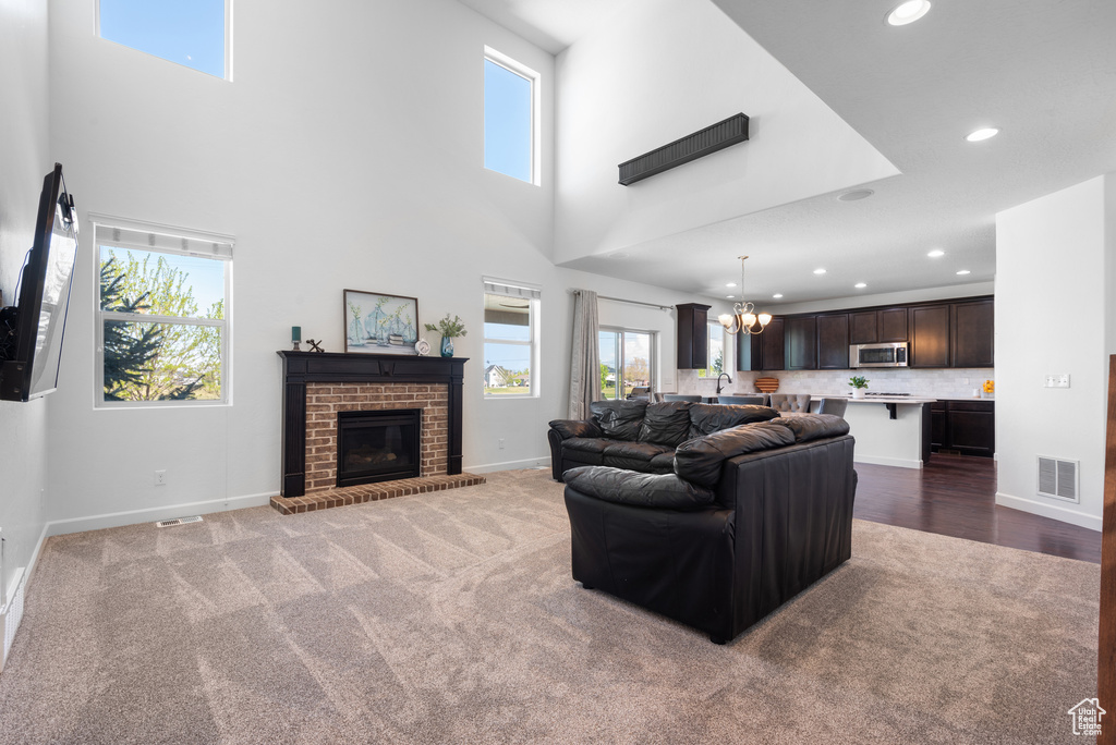Carpeted living area with visible vents, recessed lighting, baseboards, and a chandelier