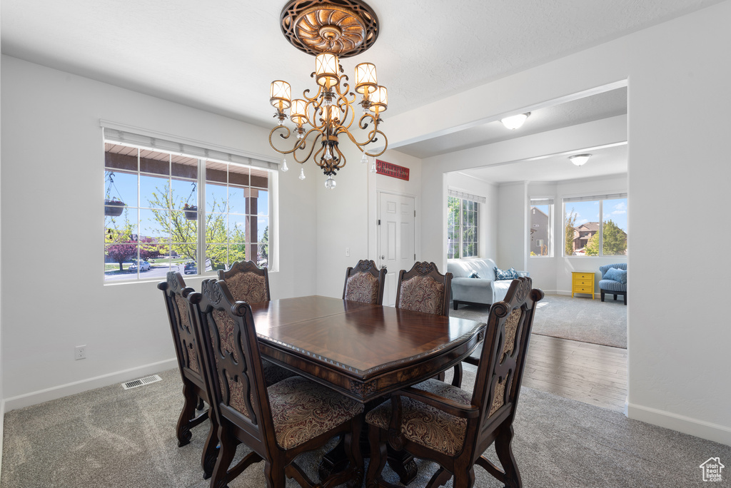 Dining space featuring carpet flooring, a chandelier, baseboards, and visible vents