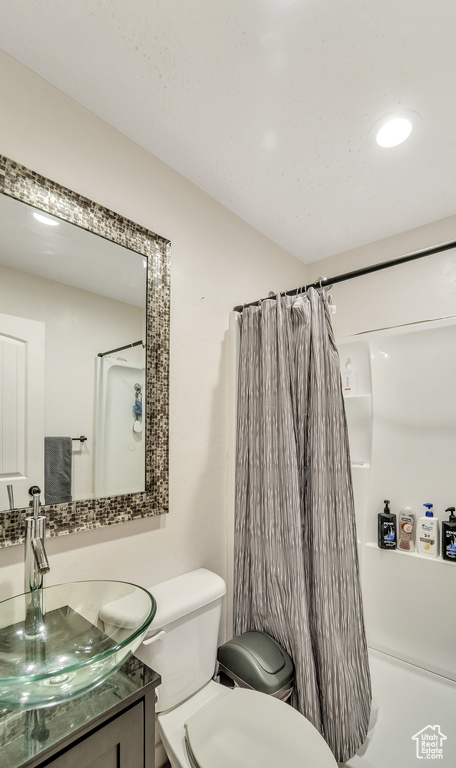 Bathroom featuring toilet, curtained shower, and vanity