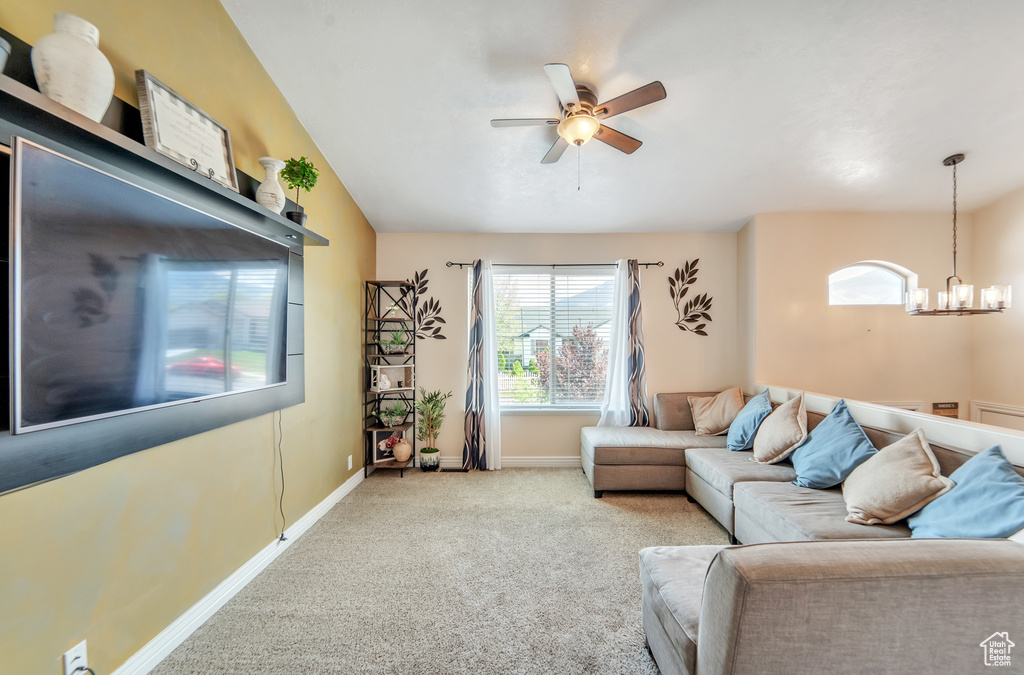 Living room featuring baseboards, carpet, and ceiling fan with notable chandelier