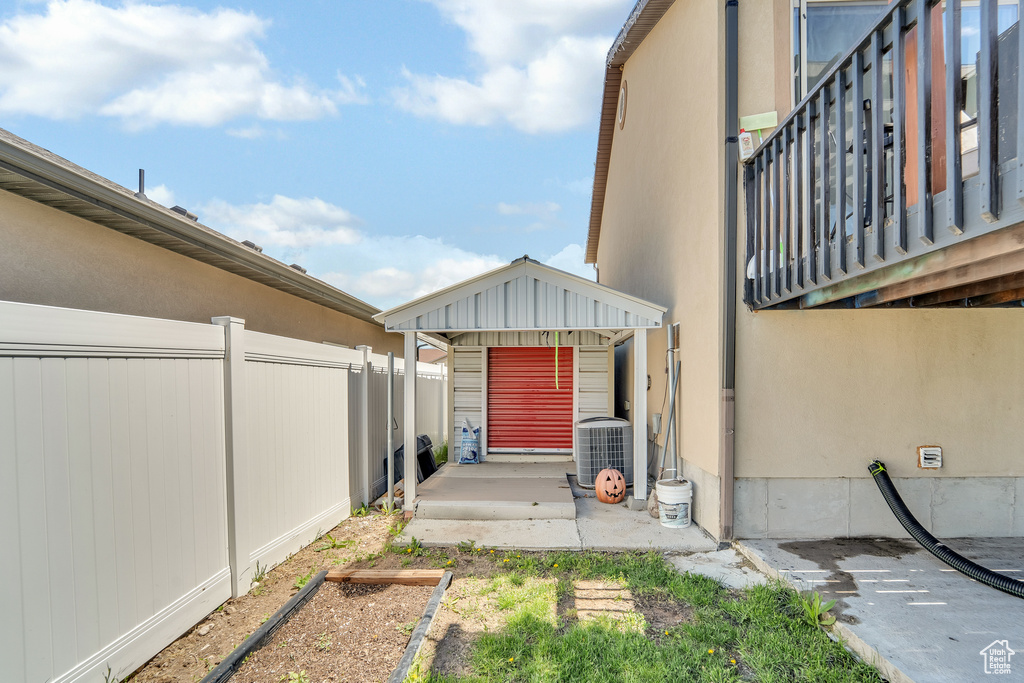 View of property exterior with a fenced backyard, a patio area, central air condition unit, and a vegetable garden