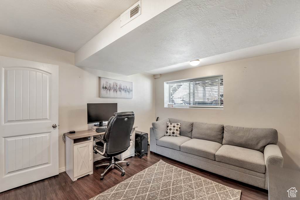 Office space featuring a textured ceiling, visible vents, and dark wood-type flooring